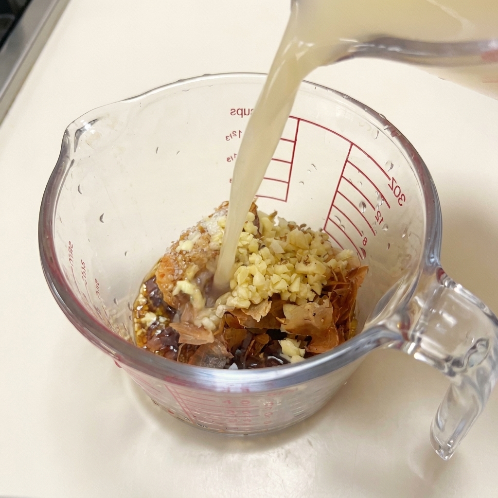 Bouillon de porc chaud versé sur le mélange de miso, dail et de bonite dans le verre doseur.