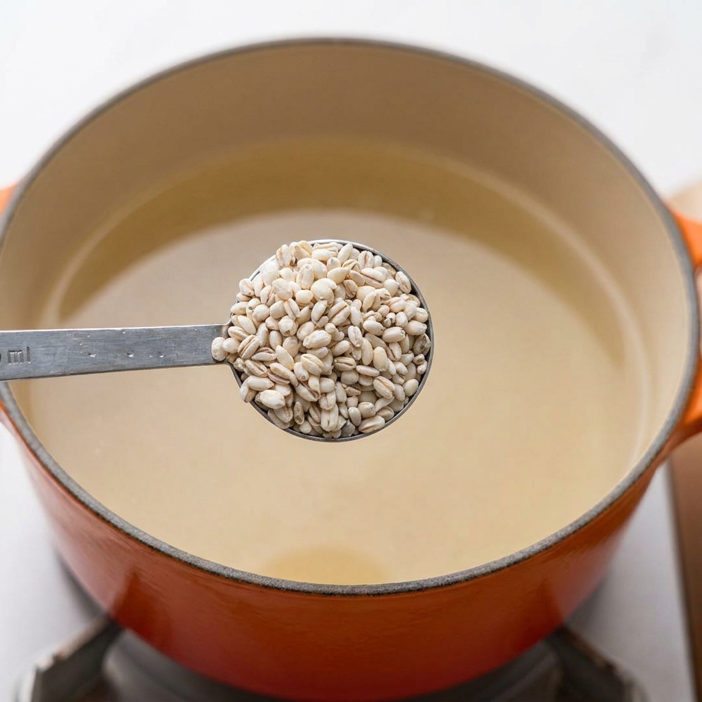 Cuillère dorge perlé entier versée directement dans une casserole deau bouillante.