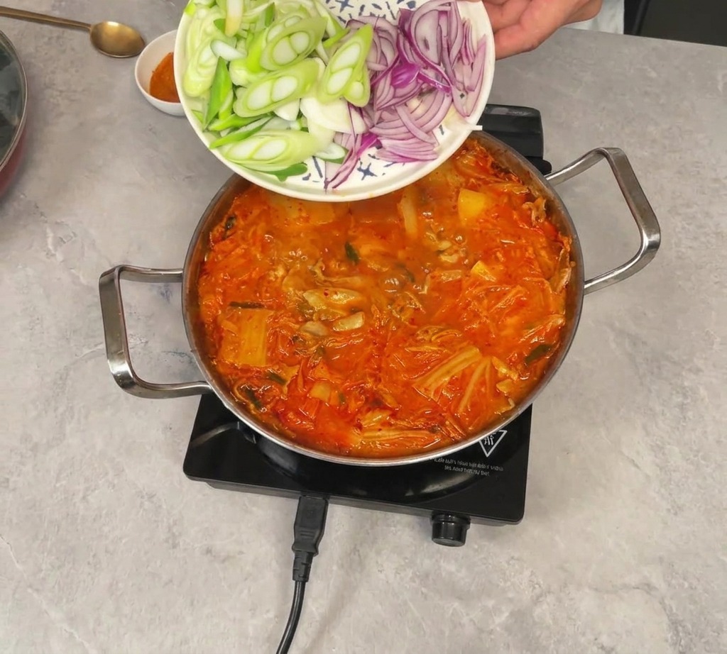 Des oignons verts et rouges émincés glissant dune assiette vers le ragoût bouillonnant.