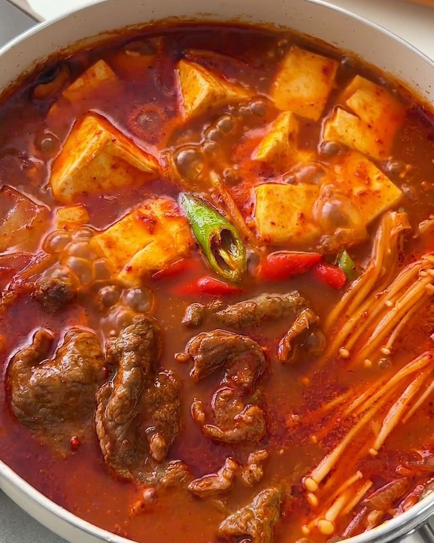 Poêle de ragoût coréen garnie de rondelles de piments verts et rouges.