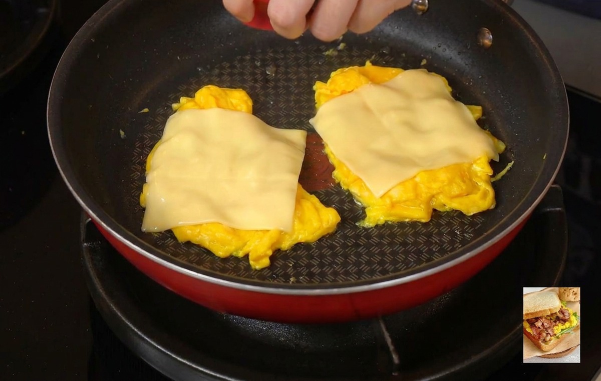 Personne plaçant un couvercle rouge sur la poêle pour emprisonner la vapeur et fondre le fromage.