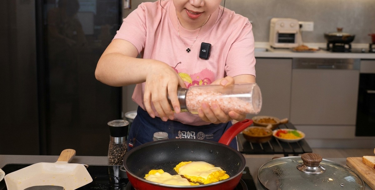 Personne utilisant un moulin à sel et poivre sur les œufs brouillés recouverts de fromage fondu.