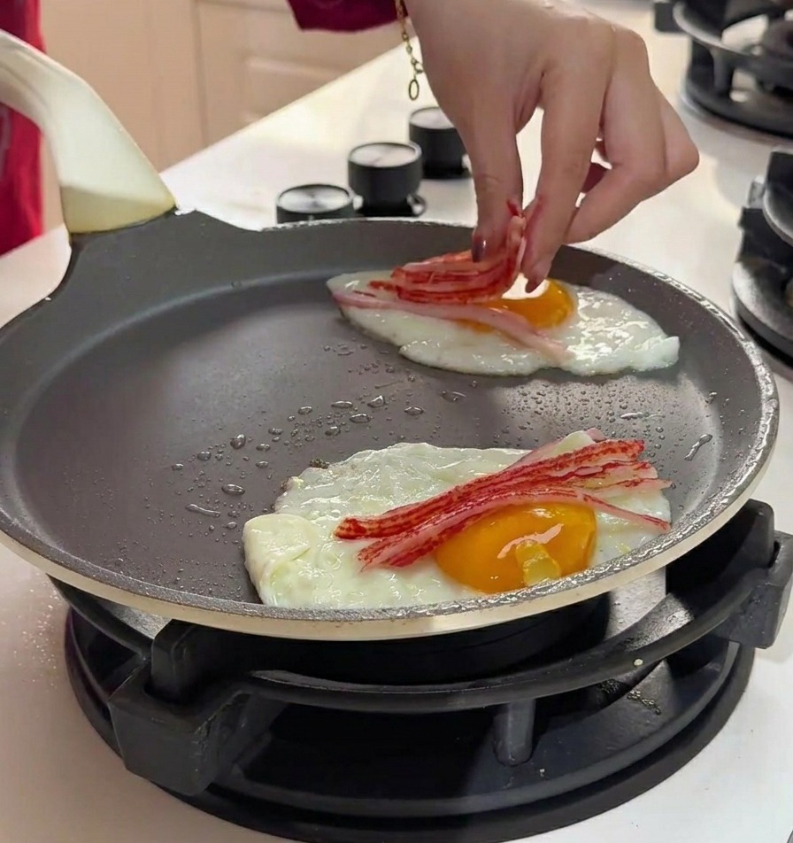 Main déposant de fines lanières de crabe effiloché sur les œufs en cuisson.