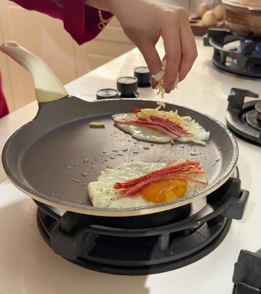 Fromage râpé saupoudré sur les œufs et le crabe dans la poêle.