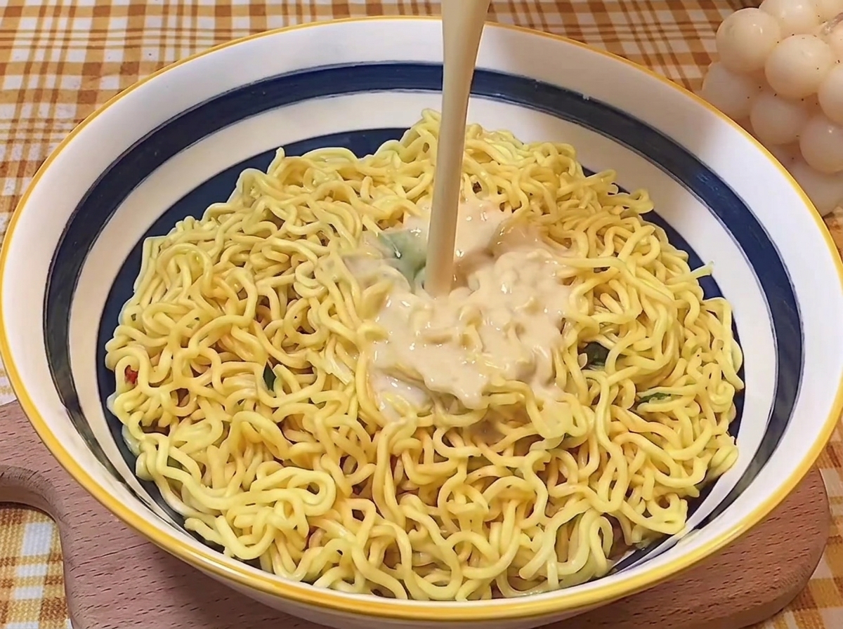 Bouillon tonkotsu riche et crémeux versé sur des nouilles ramen dans un bol de service.
