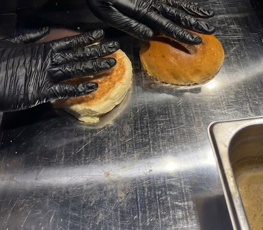 Deux pains burgers pressés à la main sur une plaque de cuisson chaude pour griller lintérieur.