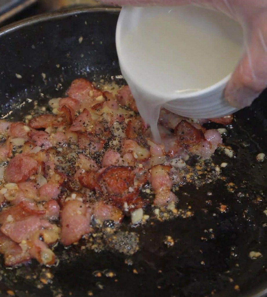 Eau de cuisson trouble versée dun bol blanc dans une poêle contenant le bacon croustillant.