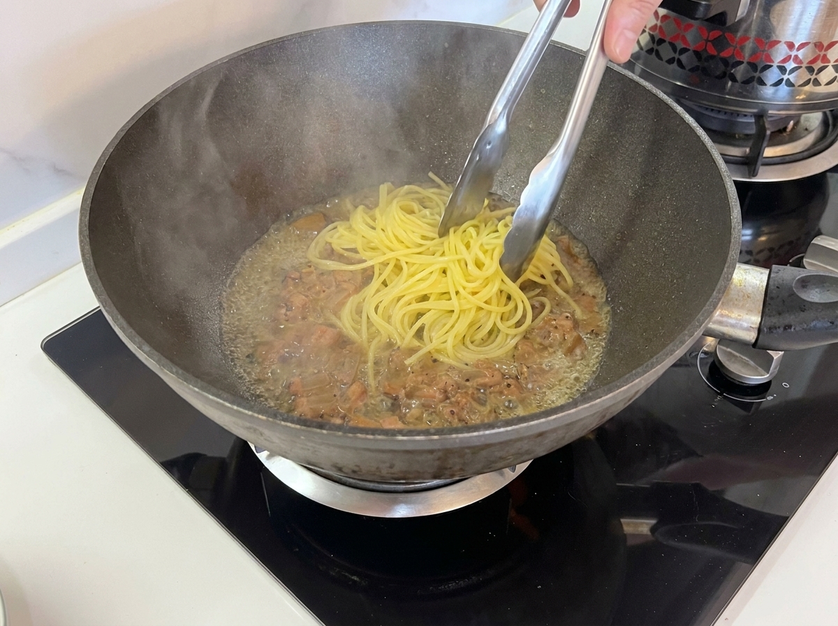 Pince soulevant les spaghetti de leau pour les mettre dans la poêle avec le guanciale.