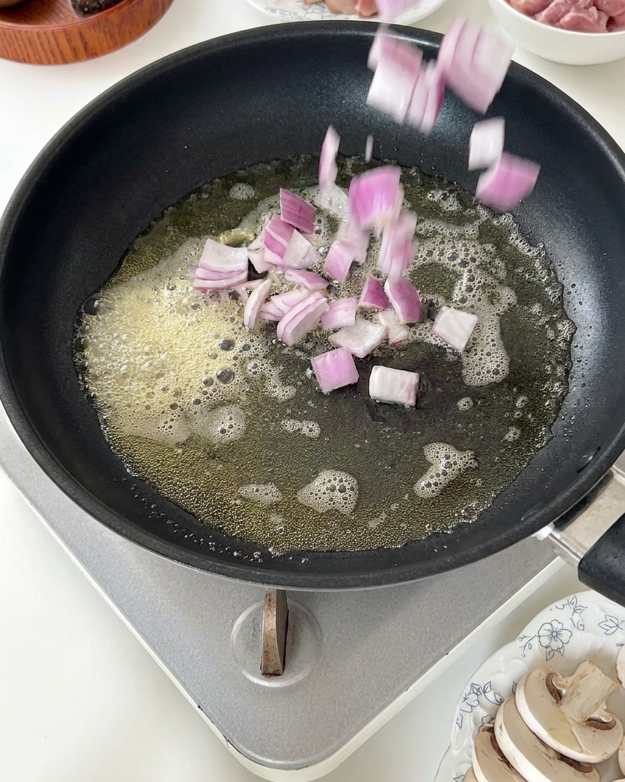 Oignons rouges dés jetés dans une poêle de beurre fondu moussant.
