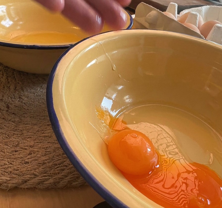 Gros plan dun jaune dœuf orange vif tombant dans un bol en émail jaune.
