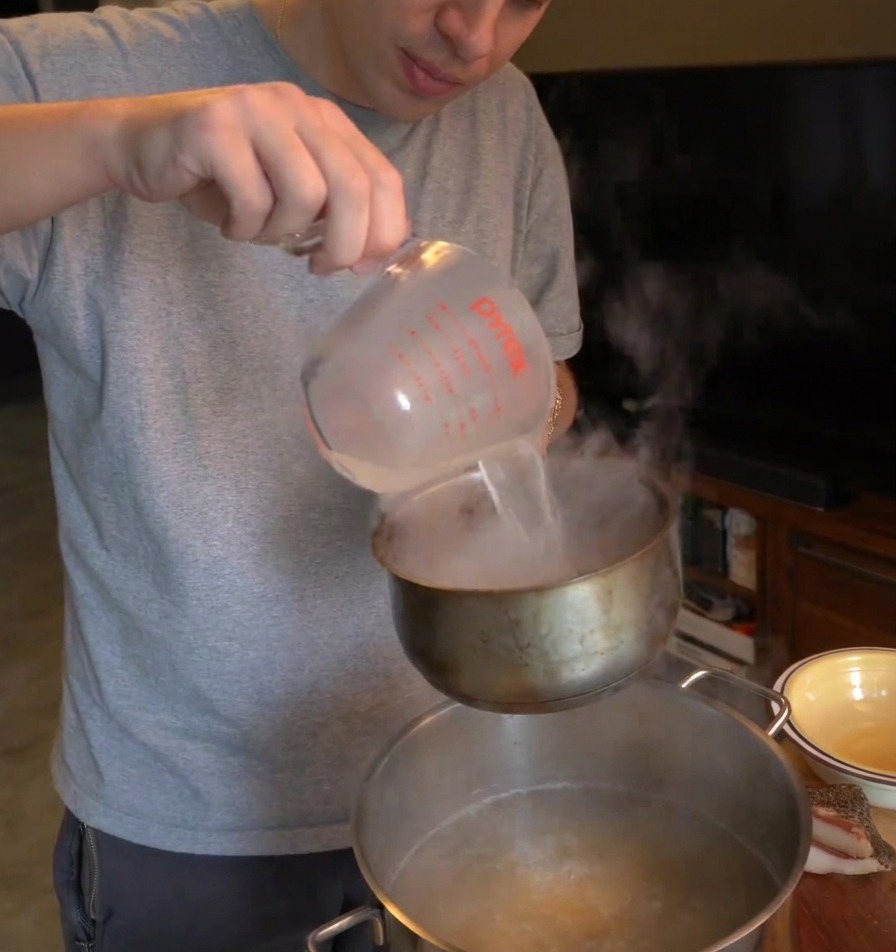 Une personne versant de leau de cuisson trouble dune louche vers un petit récipient au-dessus de la casserole.