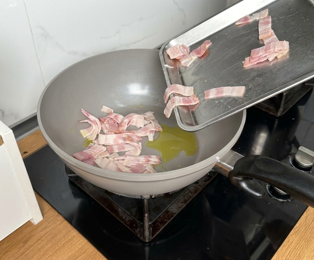 Morceaux de bacon versés dans une grande poêle avec de lhuile chaude.