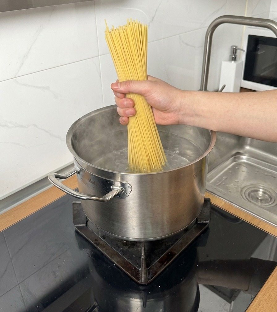 Un bouquet de spaghetti secs plongé dans une casserole deau bouillante.
