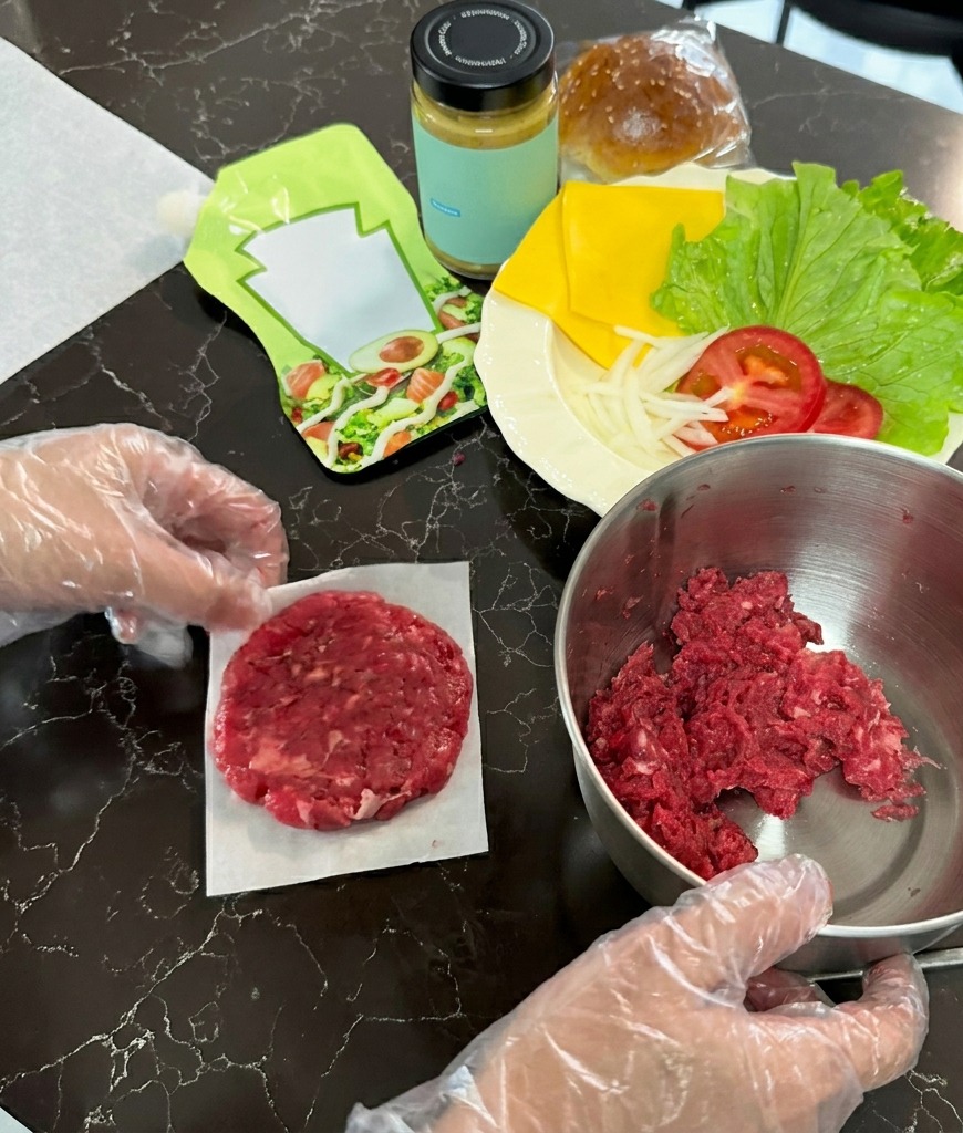 Un steak de bœuf aplati en un cercle fin sur un carré de papier sulfurisé blanc.