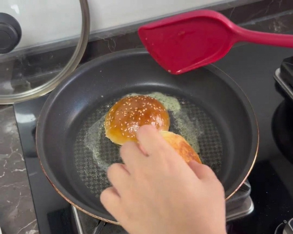 Moitiés de pains à burger toastées face contre poêle avec du beurre fondu moussant.