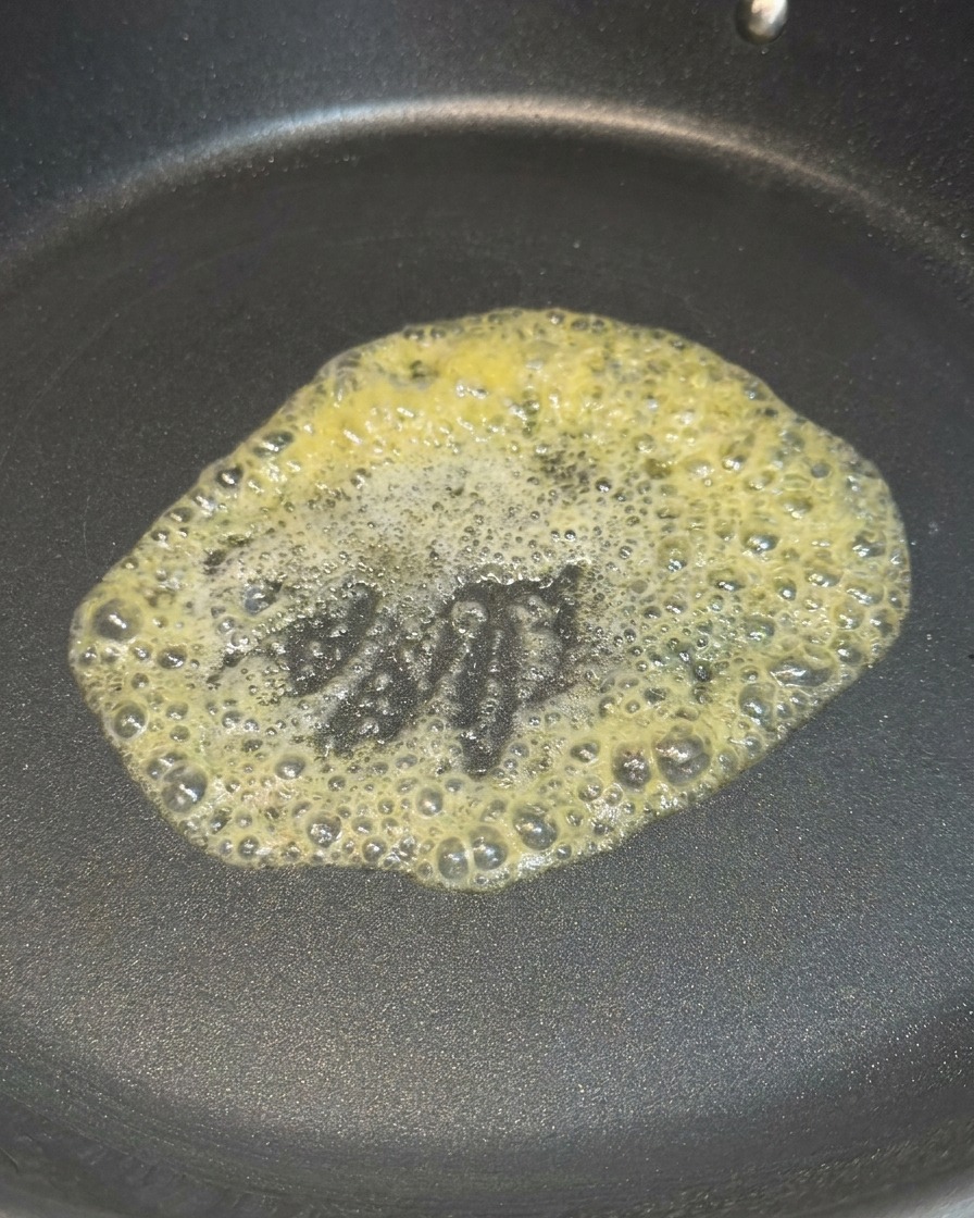 Une noisette de beurre jaune fondant et moussant au centre dune poêle antiadhésive chaude.