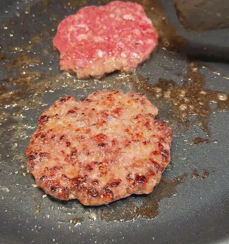 Une spatule retournant un steak de bœuf pour révéler une face bien grillée et caramélisée.