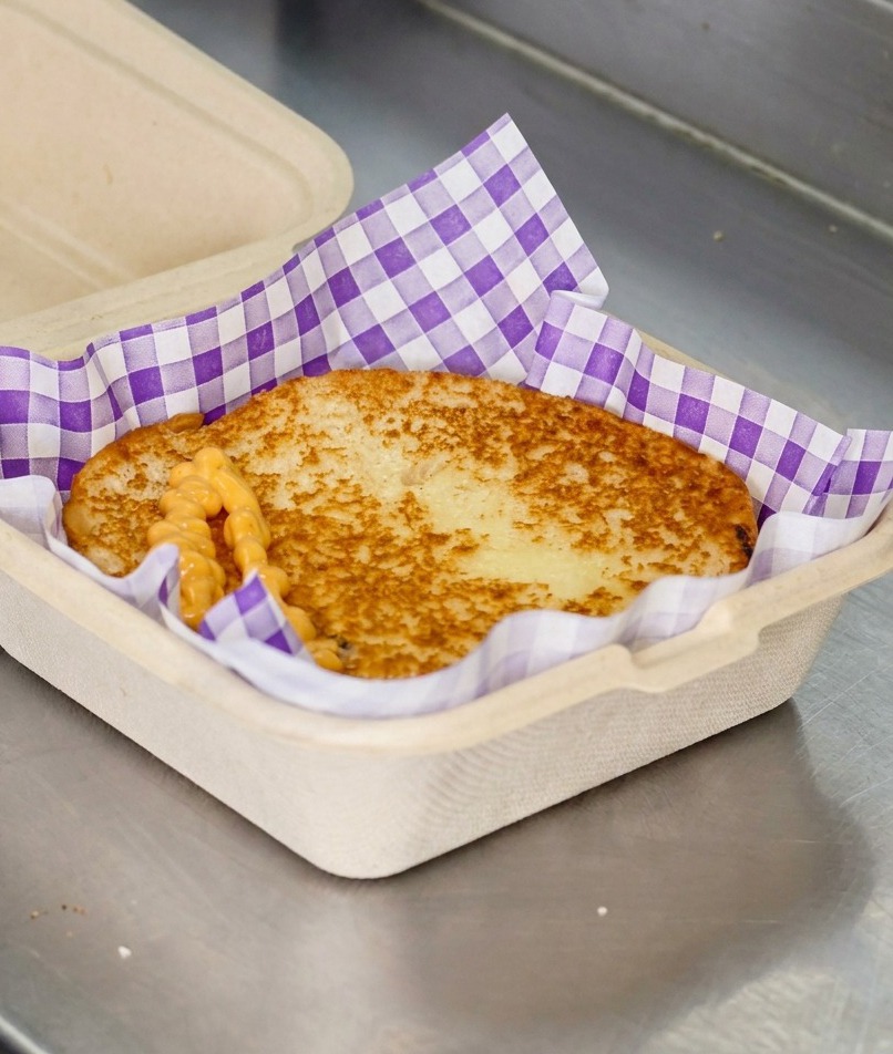 Sauce burger orange crémeuse versée en zigzag sur un pain toasté bien doré.