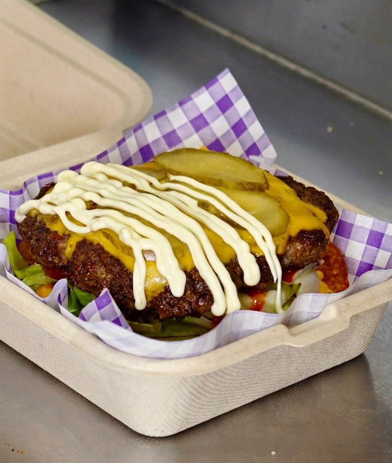 Mayonnaise blanche versée sur les rondelles de cornichons dun steak de burger.