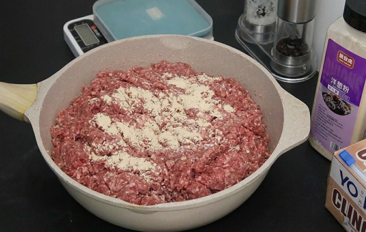 Bœuf haché cru dans un plat recouvert dune fine couche de poudre doignon et dail blanc.