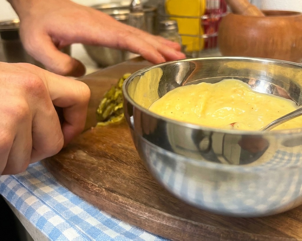 Cornichons finement hachés ajoutés à un bol de mayonnaise, moutarde et ketchup.