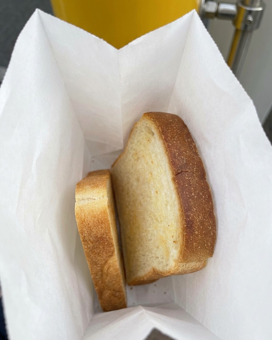 Deux tranches épaisses de pain de mie blanc reposant dans un sac en plastique doublé de papier.
