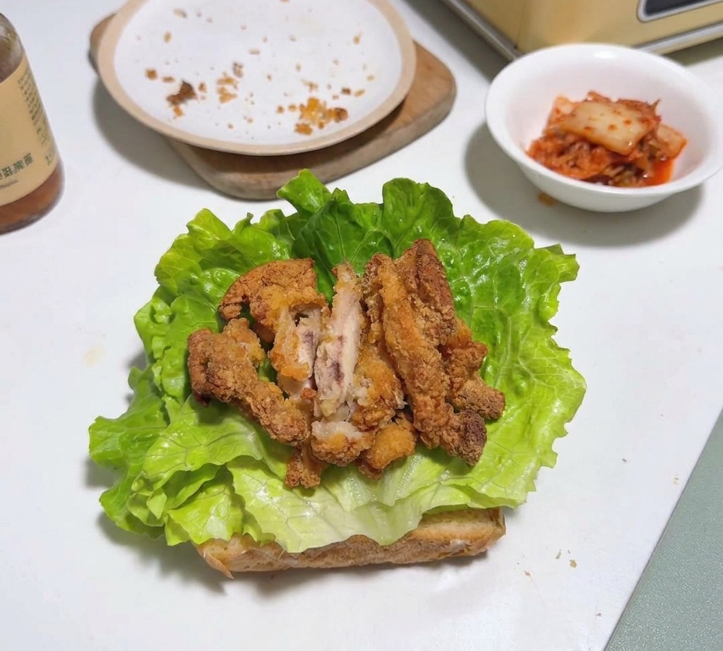 Morceaux de poulet frit disposés sur une feuille de laitue et du pain grillé.
