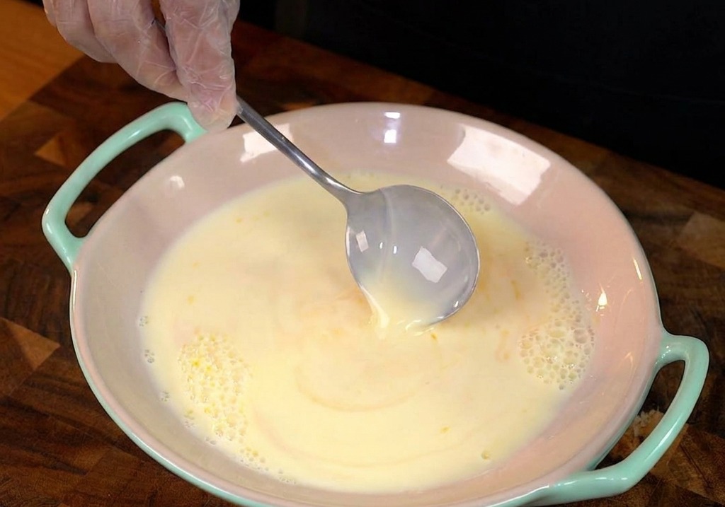 Tranche de pain de mie trempée dans lappareil à pain perdu jaune.