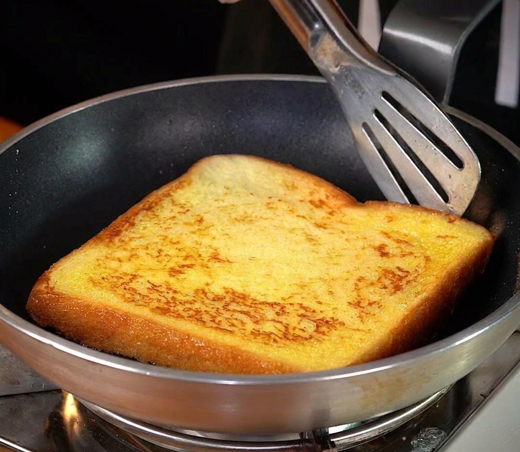Tranche de pain dorant dans une poêle avec du beurre fondu.