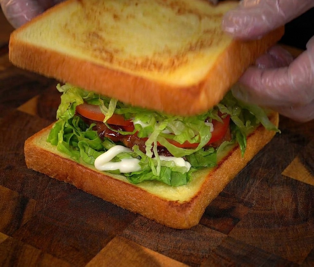 Mise en place de la dernière tranche de pain sur le sandwich à étages.