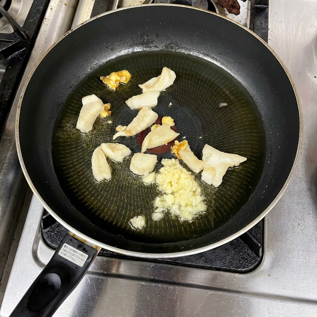 Ail haché cuisant dans lhuile chaude avec des morceaux de gras.