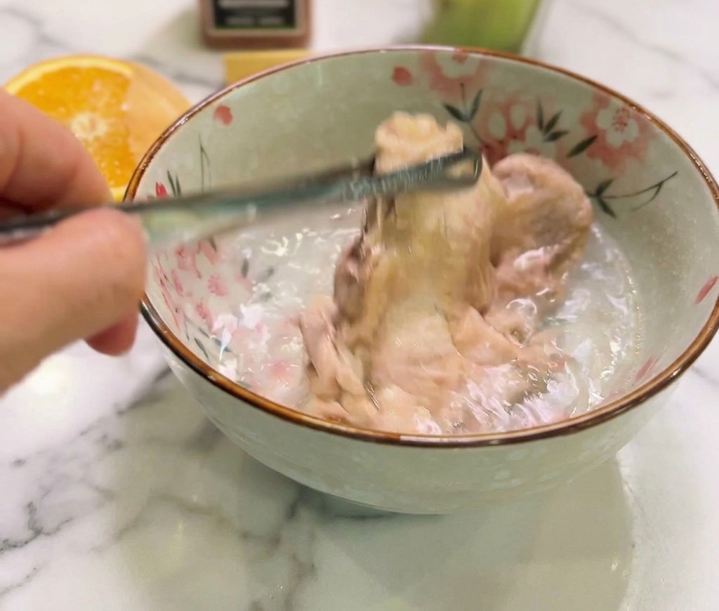 Le poulet cuit plongé dans un bol en céramique rempli deau froide pour stopper la cuisson.