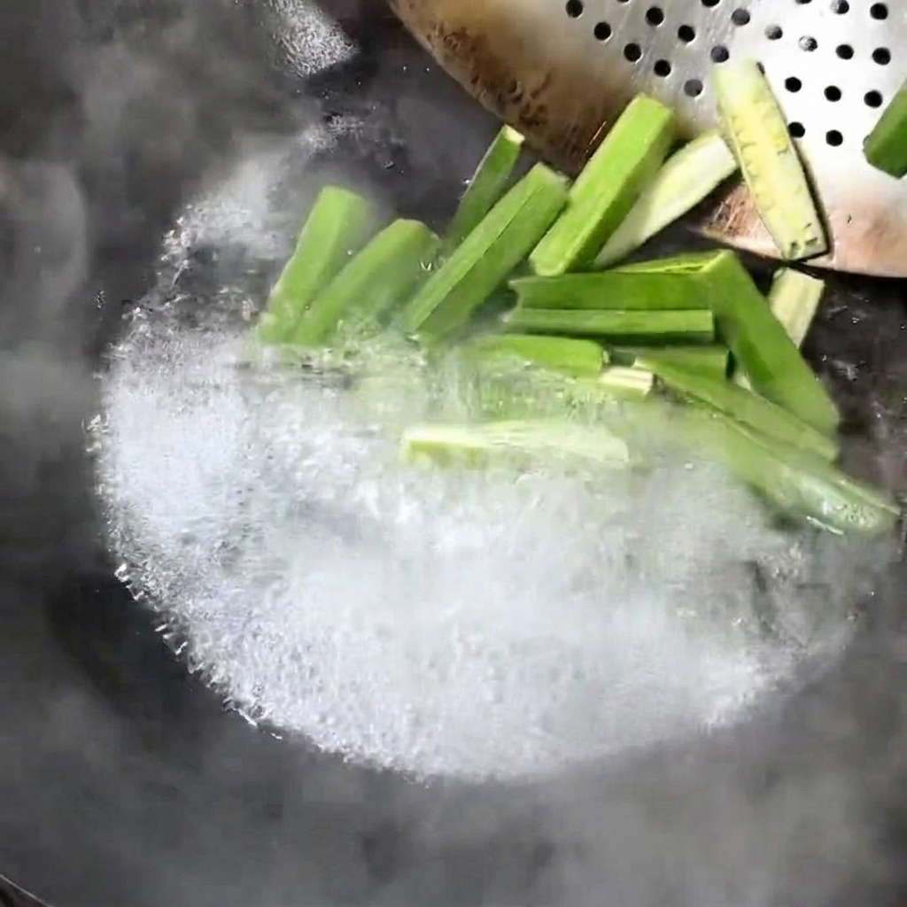 Morceaux de gombo frais en train de bouillir dans un wok.