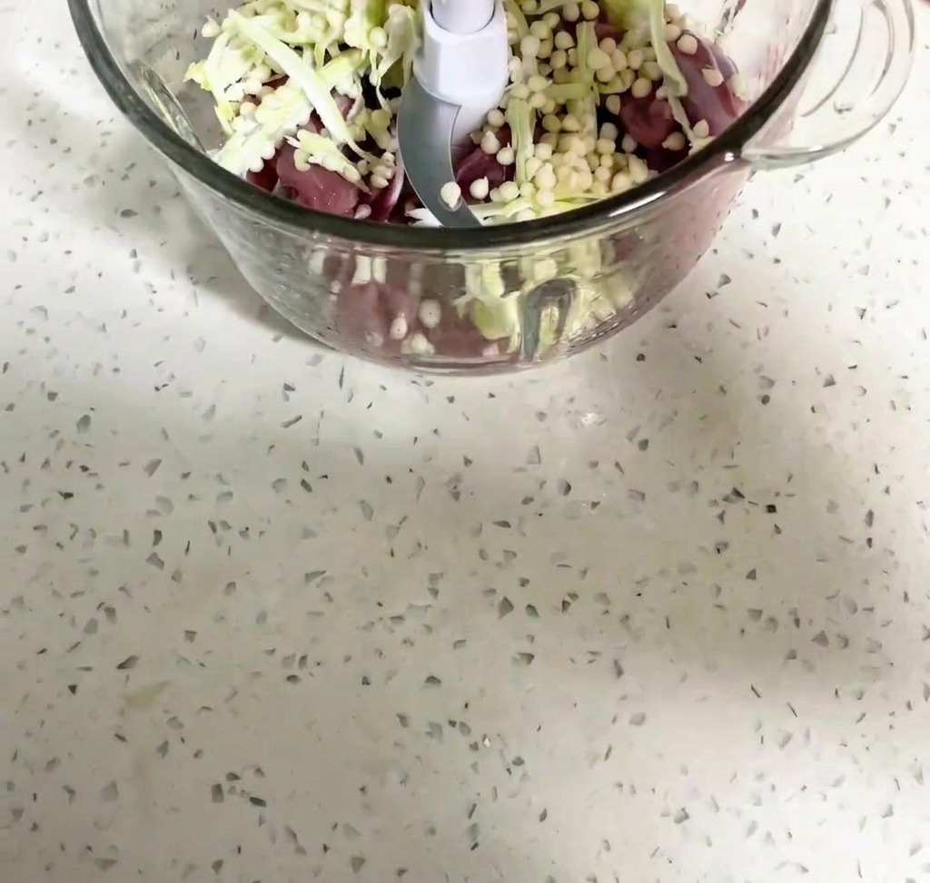 Viande de canard et graines de gombo en train dêtre mixées dans le bol dun robot culinaire.