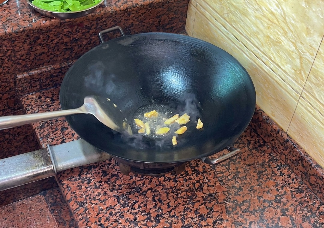 Morceaux de peau de canard sautant dans un wok chaud, libérant de la graisse liquide.