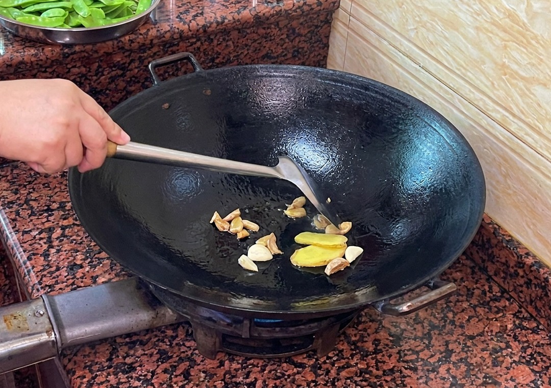 Tranches de gingembre et dail sautant dans la graisse de canard fondue dans un wok.