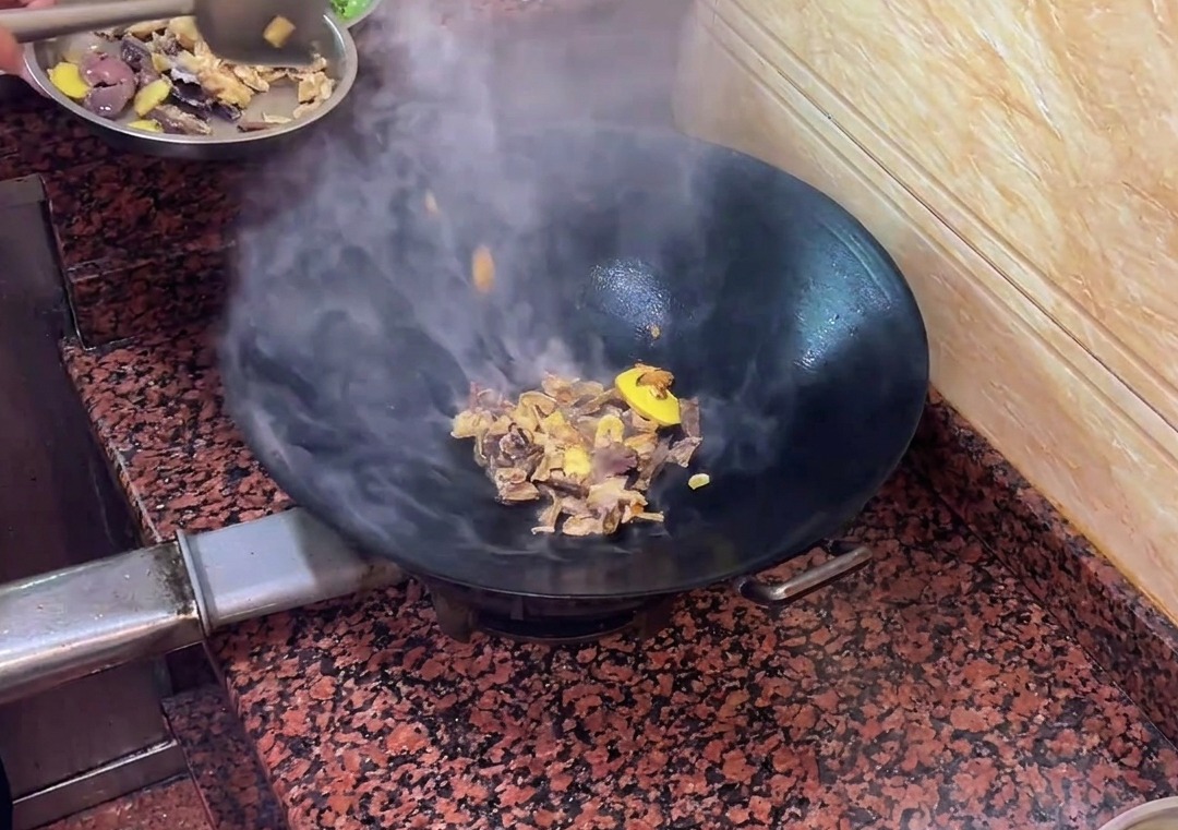 Morceaux de saucisse de foie de canard sautant avec les aromates dans le wok.