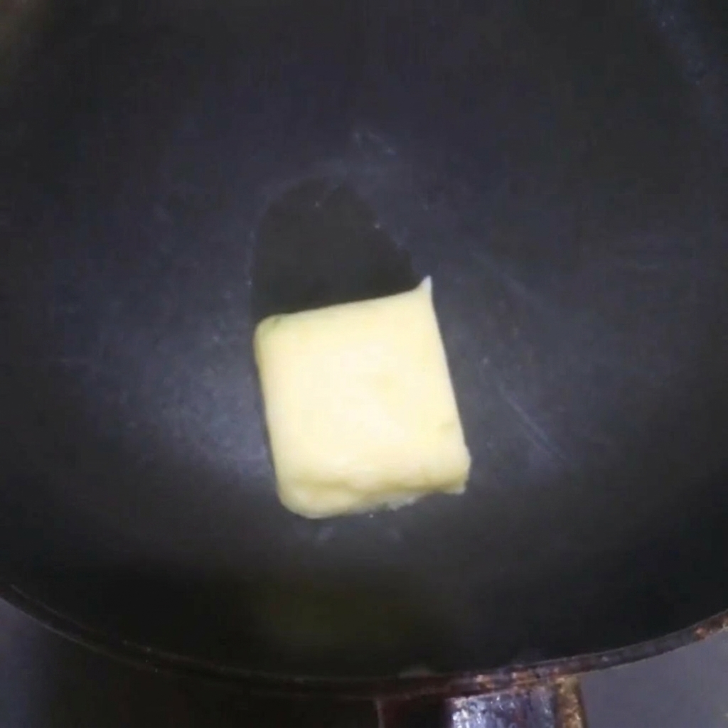Du beurre jaune en train de fondre et grésiller dans une poêle chaude.