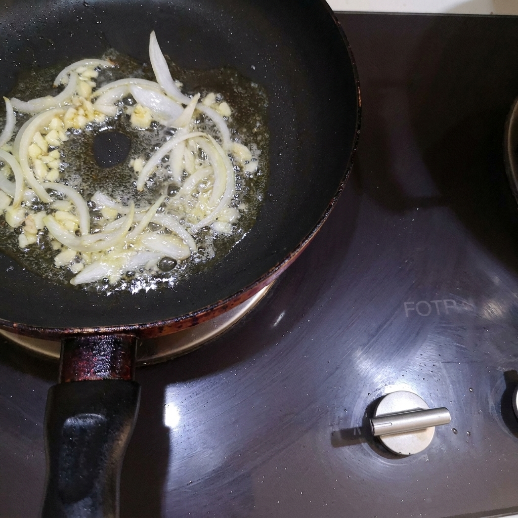 Oignons et ail hachés mélangés dans le beurre fondu dune poêle.