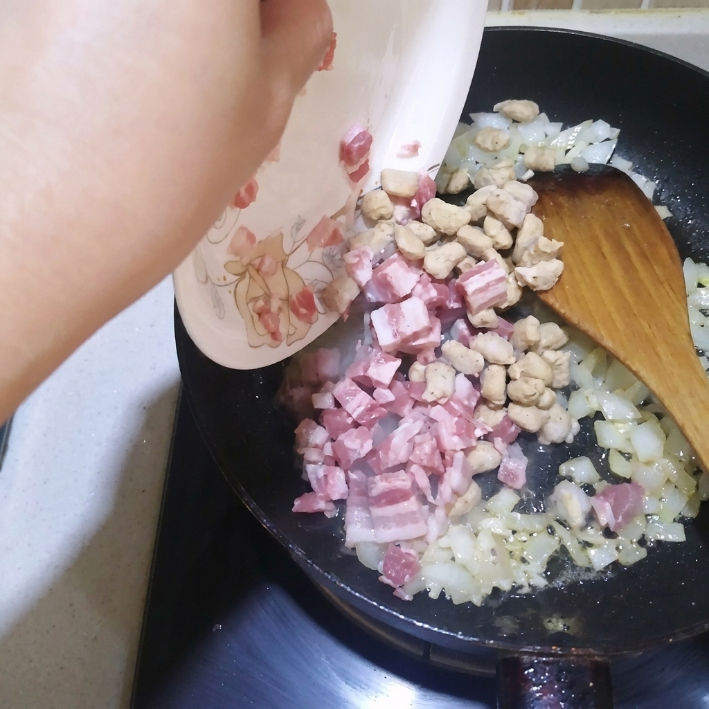 Dés de lard et cubes de bœuf sautés dans une poêle avec des oignons et de lail.