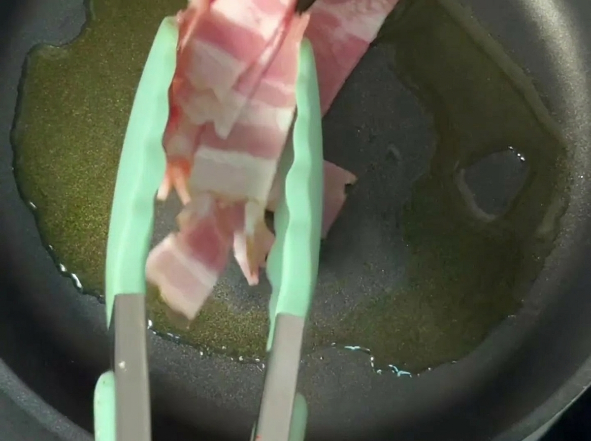 Lamelles de bacon croustillantes qui dorent dans de lhuile dolive dans une poêle antiadhésive.