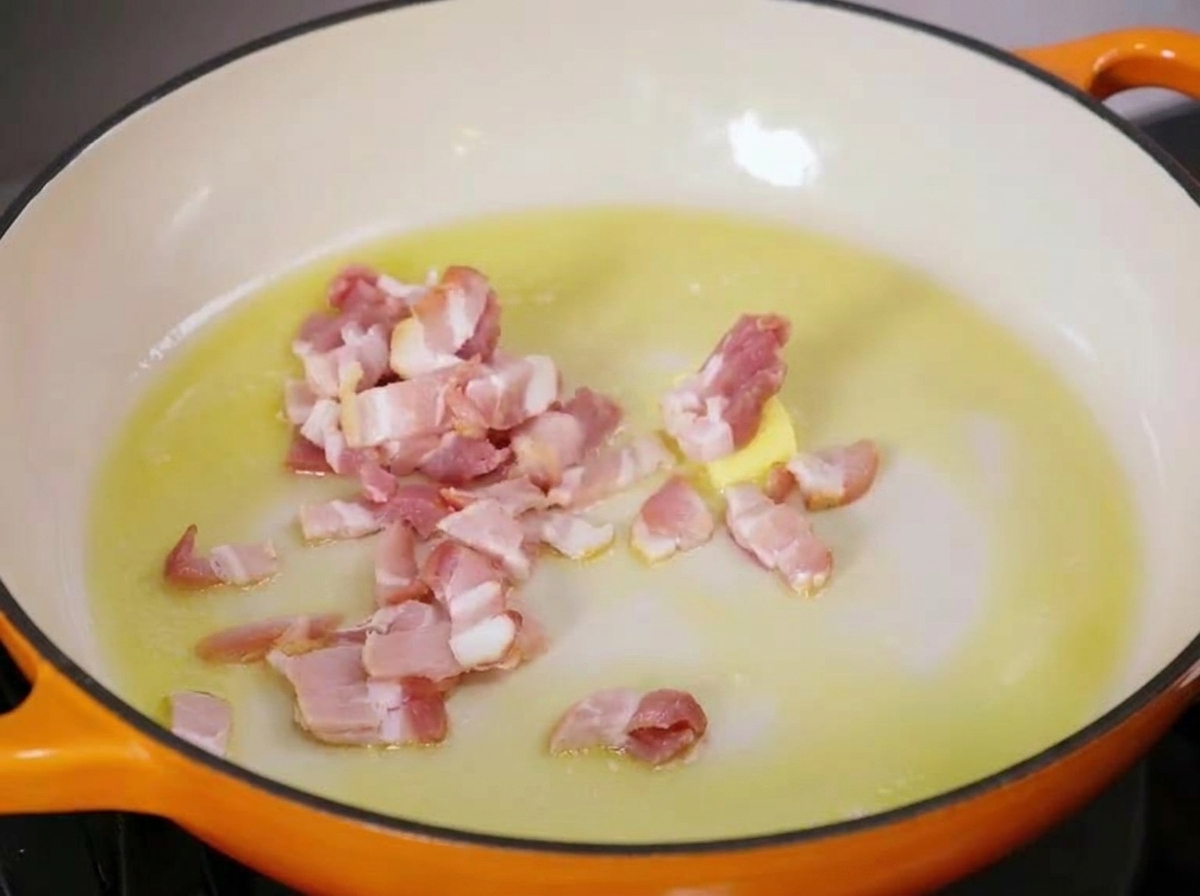 Des morceaux de lard cru grésillant dans une poêle chaude avec du beurre fondu et de lhuile dolive.