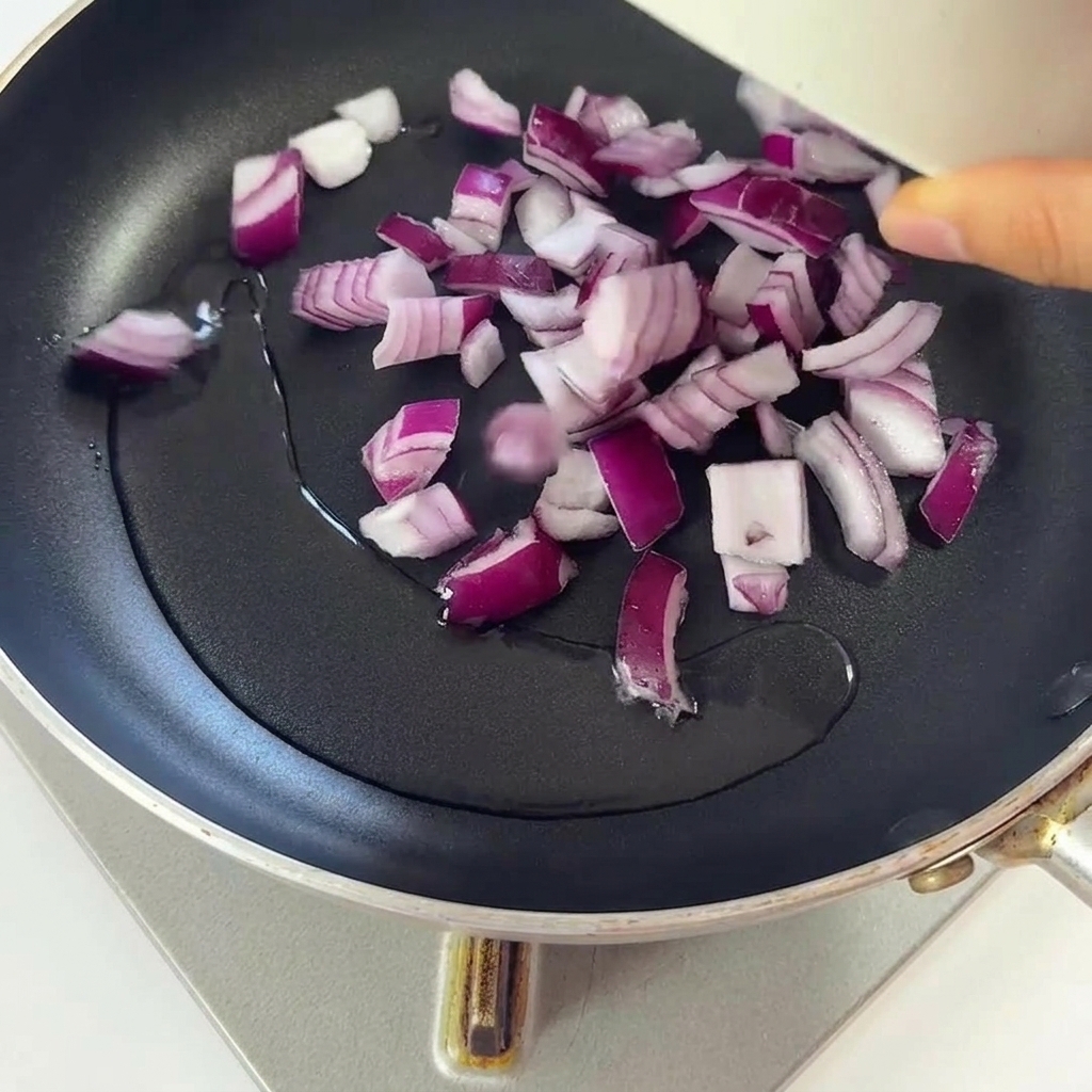 Oignons rouges hachés frisant dans une poêle avec de lhuile bien chaude.