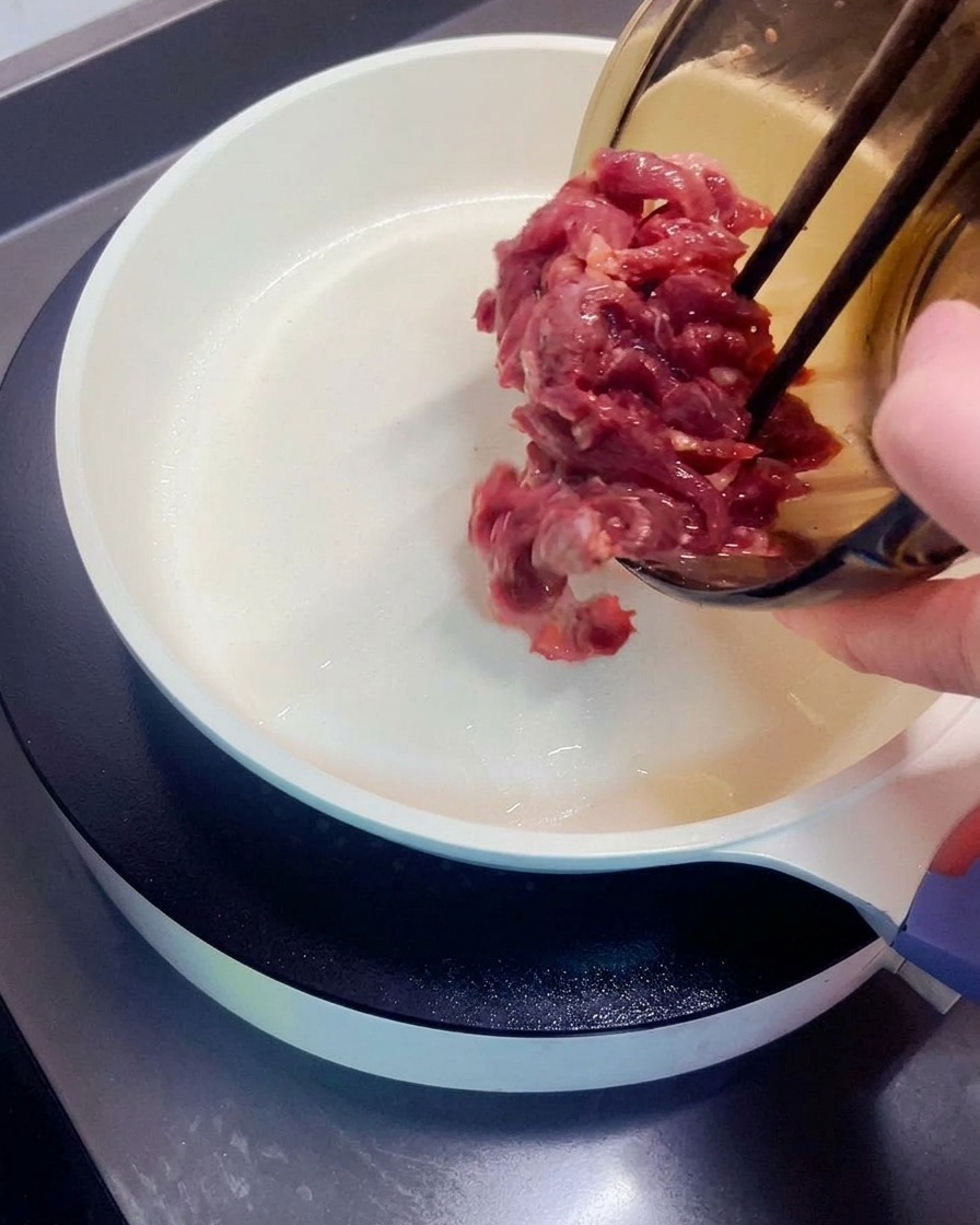 Morceaux de bœuf mariné transférés dans une poêle chaude.