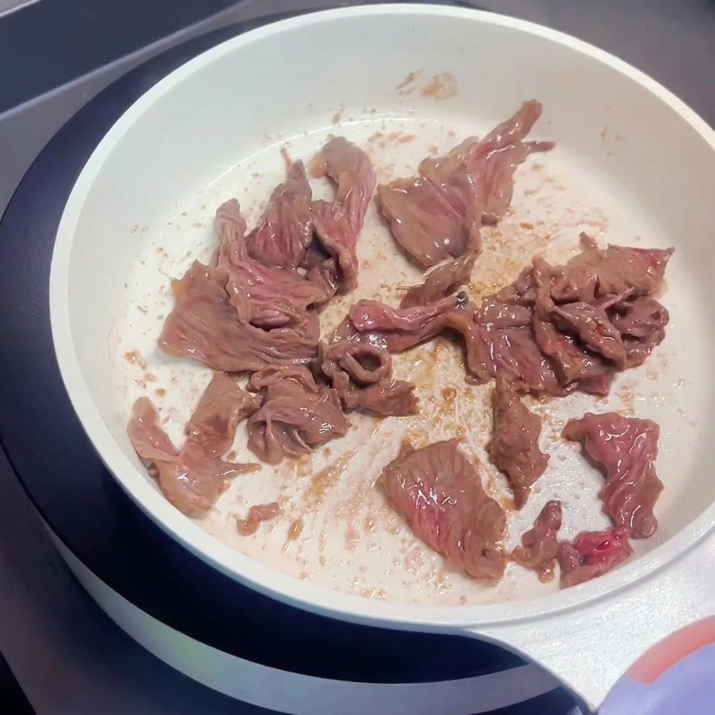 Tranches de bœuf sautées dans une poêle, montrant des surfaces dorées.