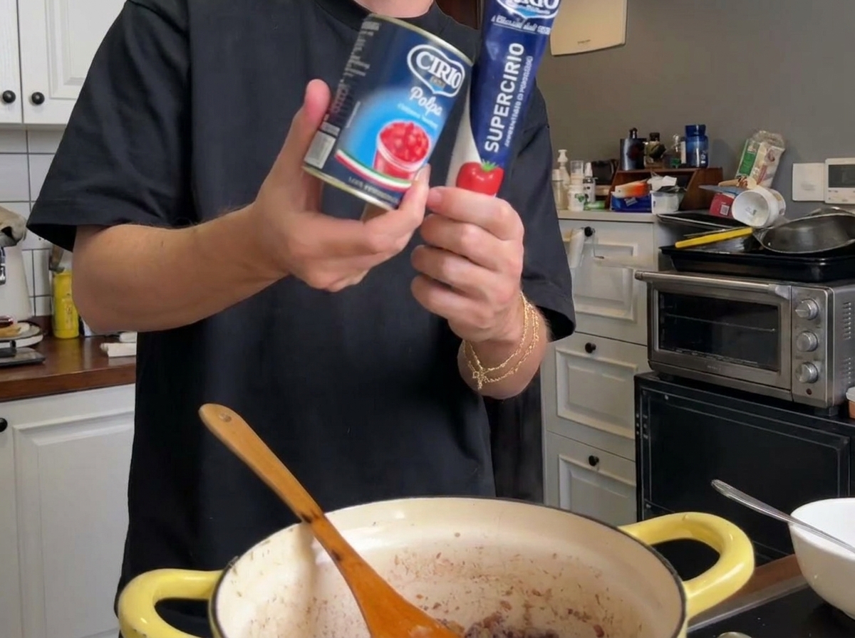 Purée de tomates en boîte et un tube de concentré de tomate tenus au-dessus de la casserole.