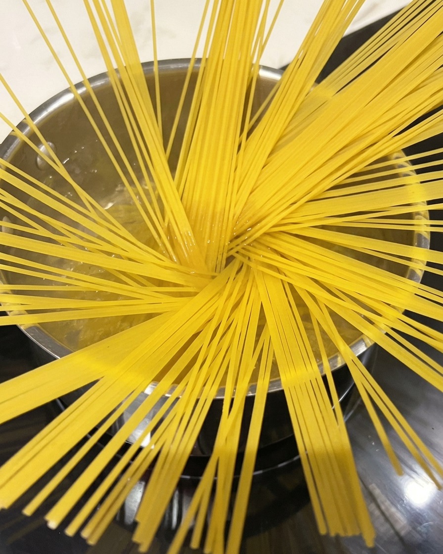 Spaghettis bouillant dans une grande casserole deau, vapeur sen échappant.