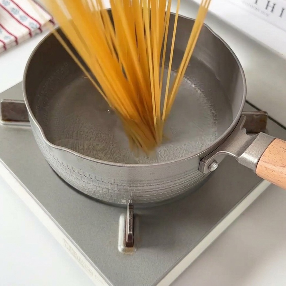 Longs brins de spaghettis immergés dans une casserole deau bouillante.