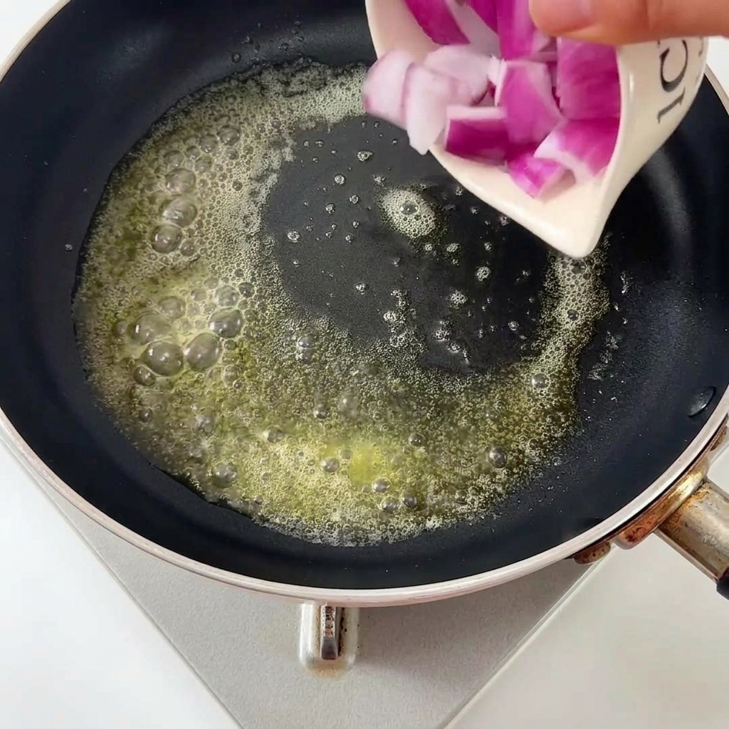 Oignons coupés en dés versés dans une poêle avec du beurre fondu.