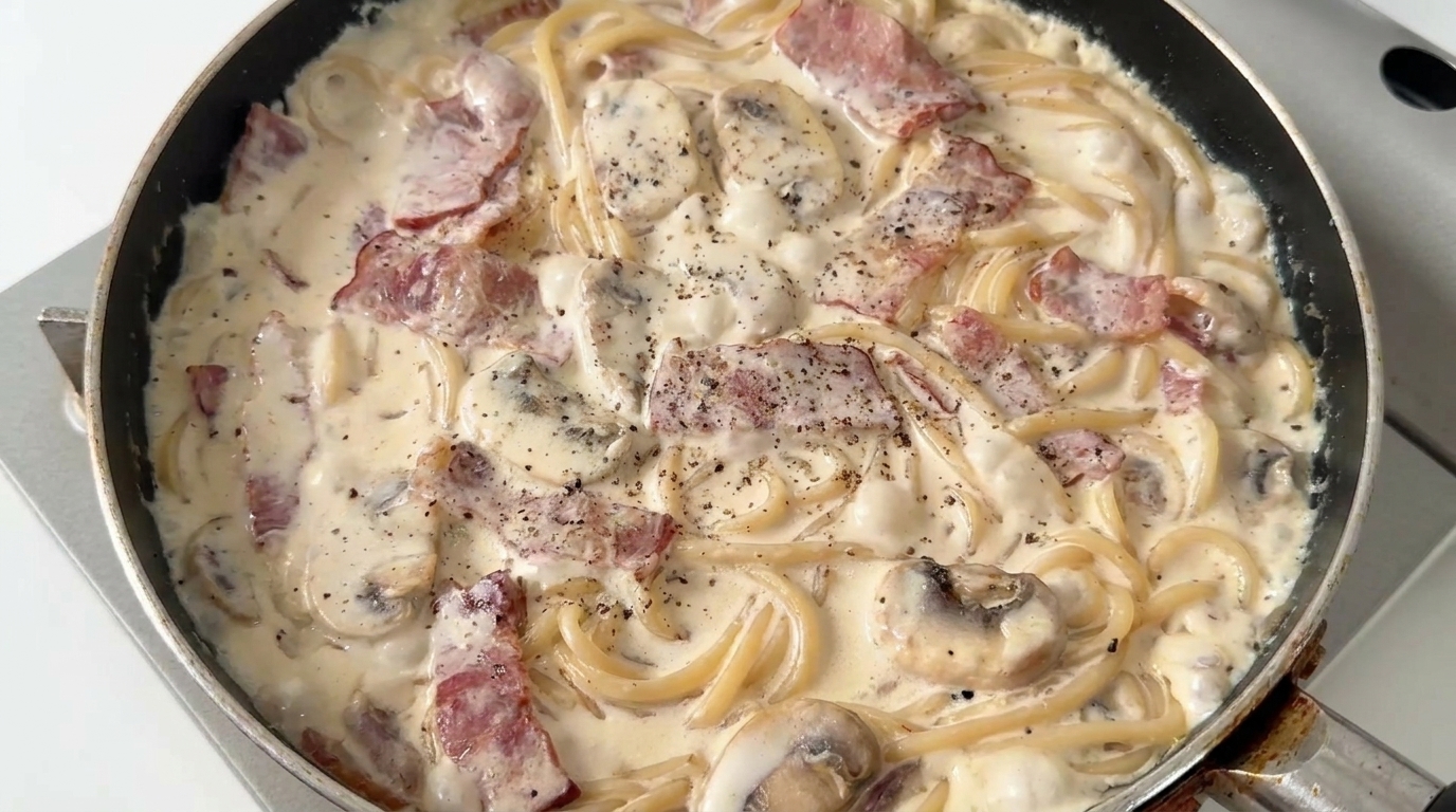 Spaghettis crémeux aux champignons et lardons fraîchement préparés, enrobés dune sauce riche avec du poivre noir concassé.